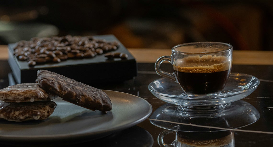 A close up of an espresso shot and chocolate cookies