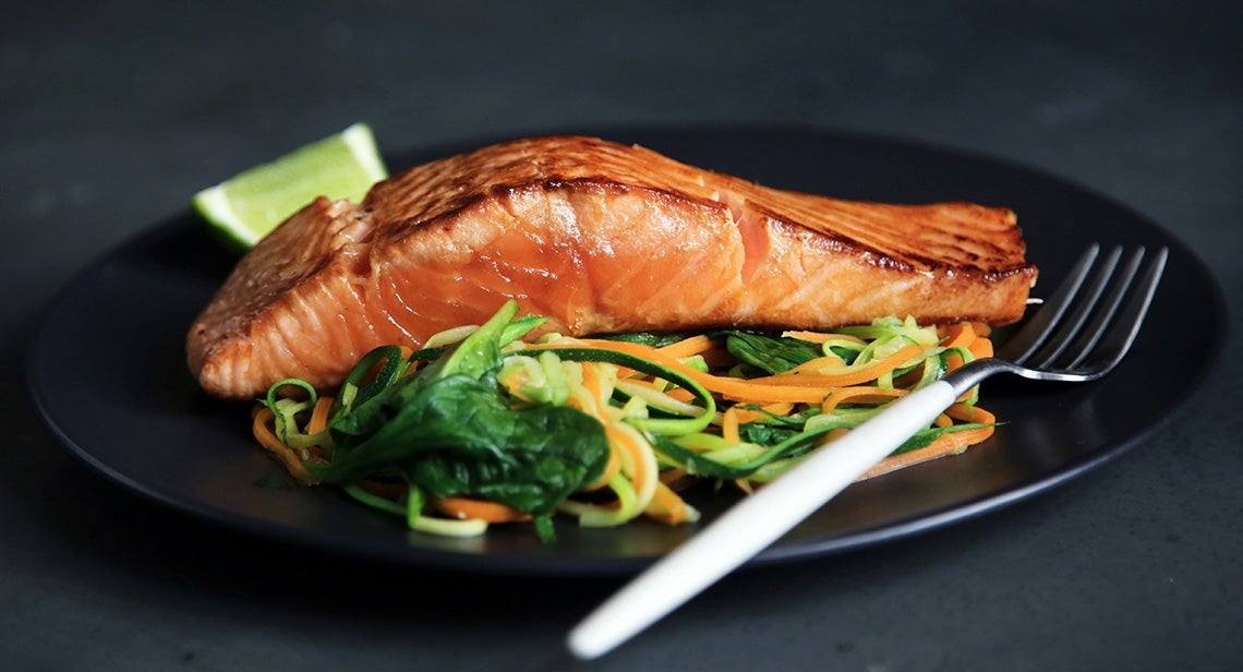 A close up of a piece of salmon with shredded vegetables