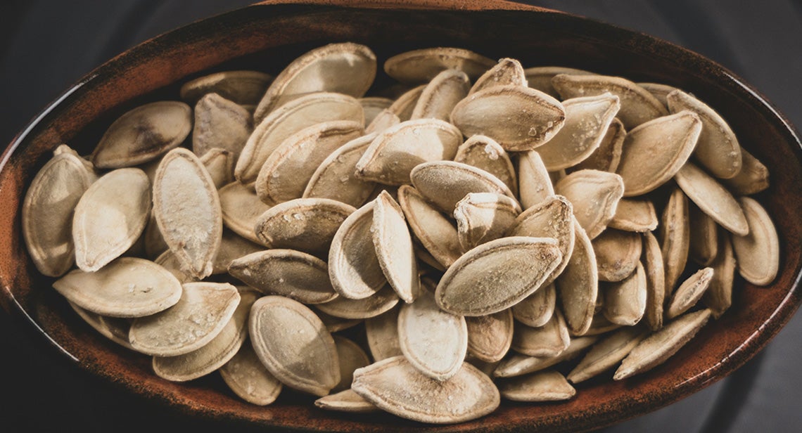 A close up of a bowl of pumpkin seeds