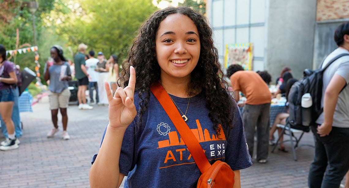 A UT student poses while making the Hook ’em hand sign
