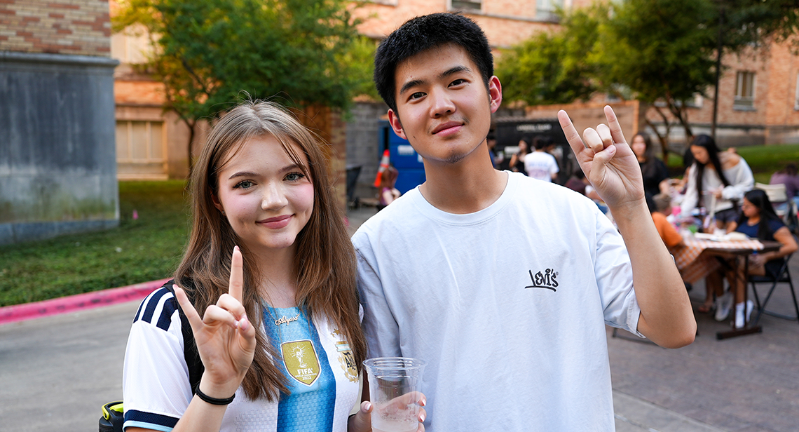 Two UT students pose with a Hook ’em hand sign