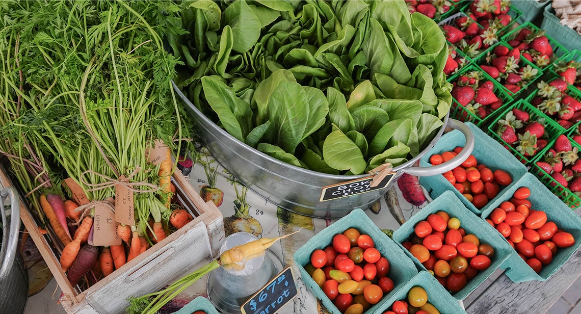 A close up of produce featuring carrots, bok choy, cherry tomatoes and strawberries