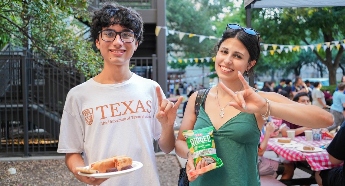 Two UT students pose together while making the Hook ‘Em hand sign at an event in the BRP Courtyard. 