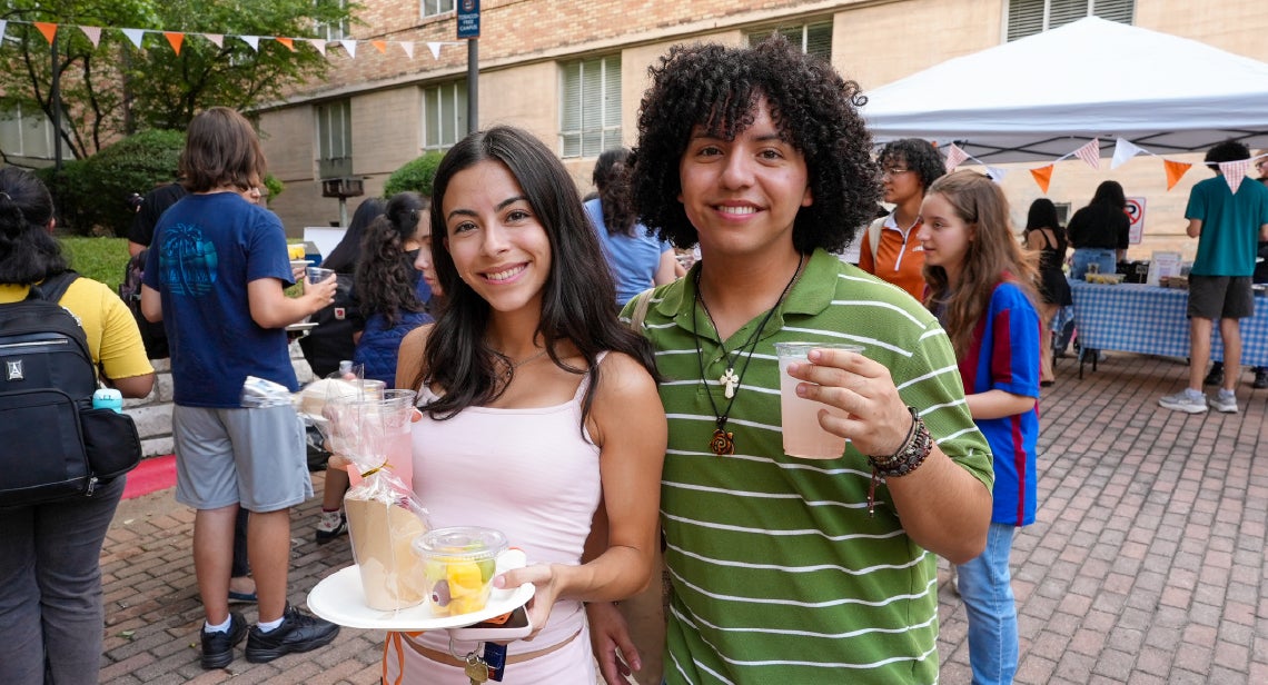 Two UT students posing with a smile and their refreshments in the BRP courtyard.