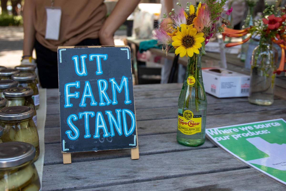 UT Farm Stand Market - sign, flowers and flyer on wooden table
