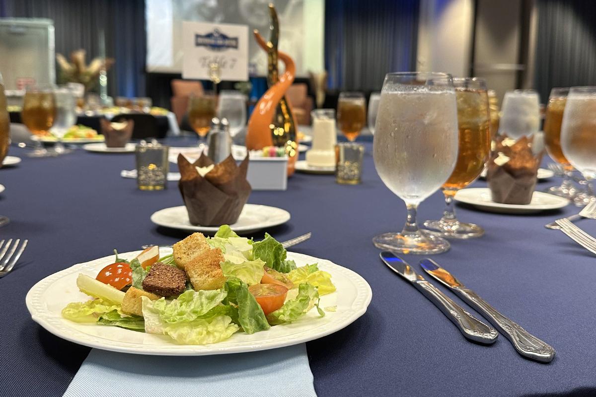 A close-up view of a salad, silverware, and glasses filled with water and iced tea at a private event catered by Forty Acres Catering