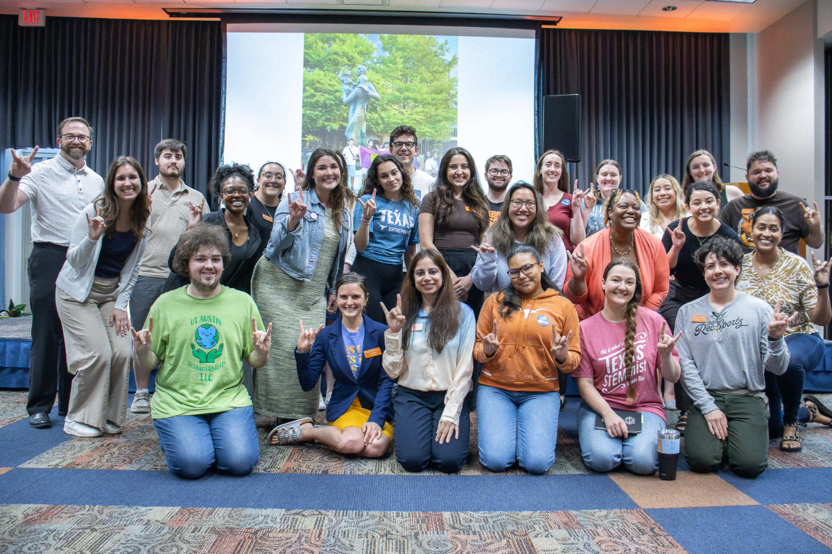 Group of LLC students and staff posing with a Hook ‘em hand sign in the San Jacinto Multipurpose Room