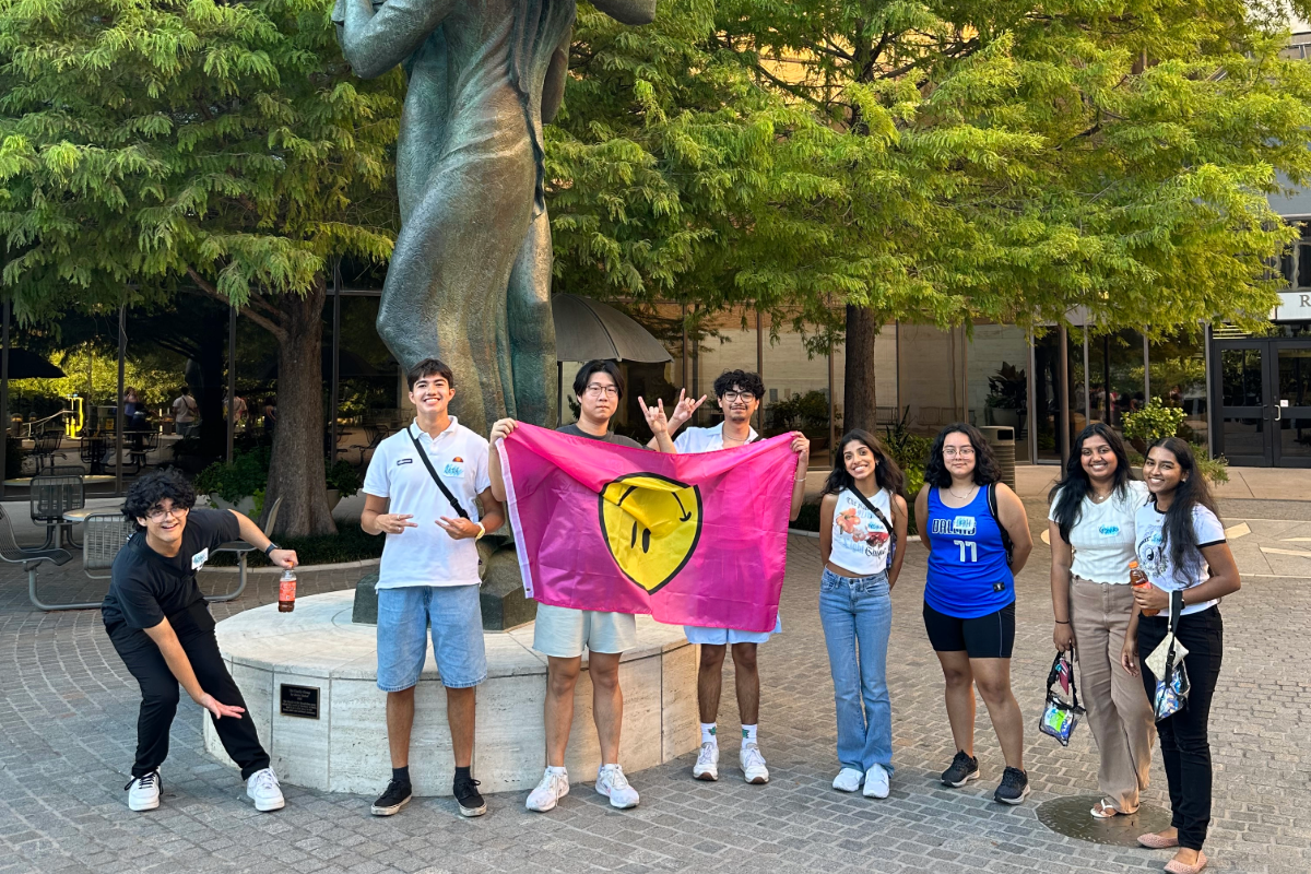 Group of LLC students posing with a flag outside of the McCombs School of Business at UT