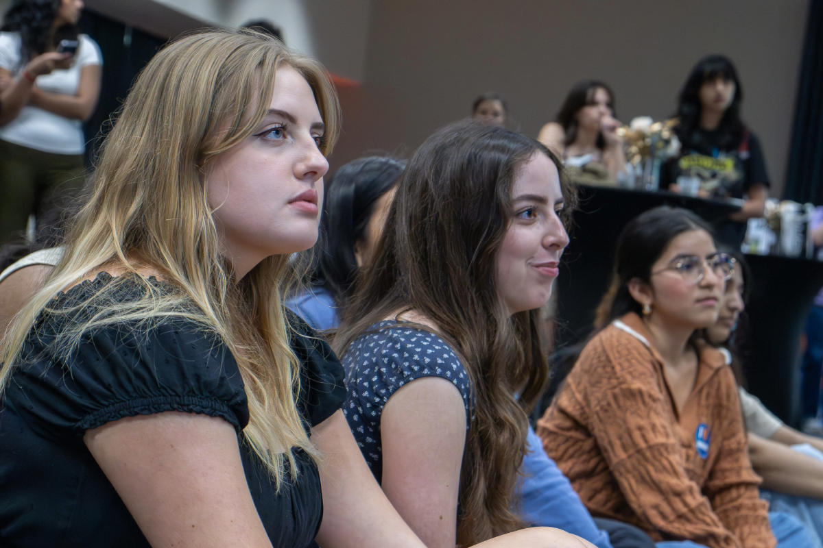 Three UT students listening to a presentation at an LLC event
