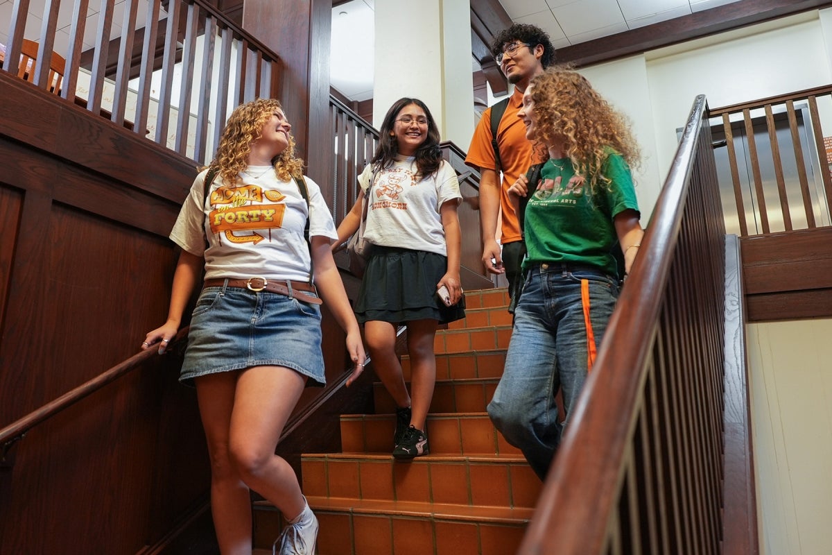 Students in Duren Four UT students wearing UT shirts walk down the stairs in Duren Hall.