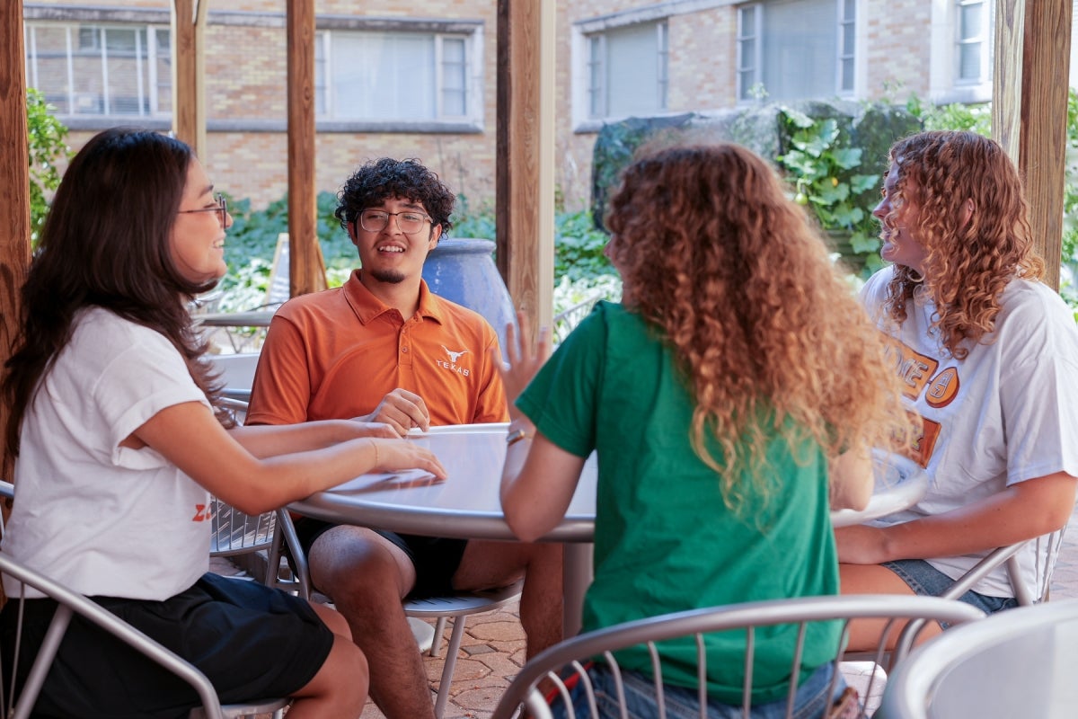 Students at Kinsolving Four UT students wearing UT shirts converse outside Kins Dining.