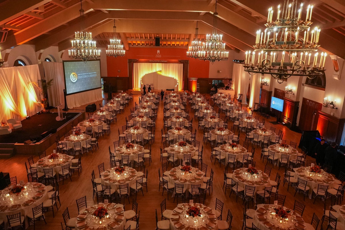 An aerial view of the Texas Union ballroom filled with round banquet tables set for a formal event