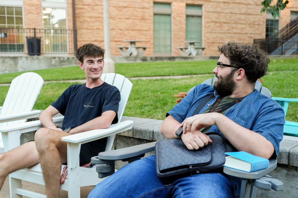 Two UT students converse at the San Jacinto Hall amphitheater. 