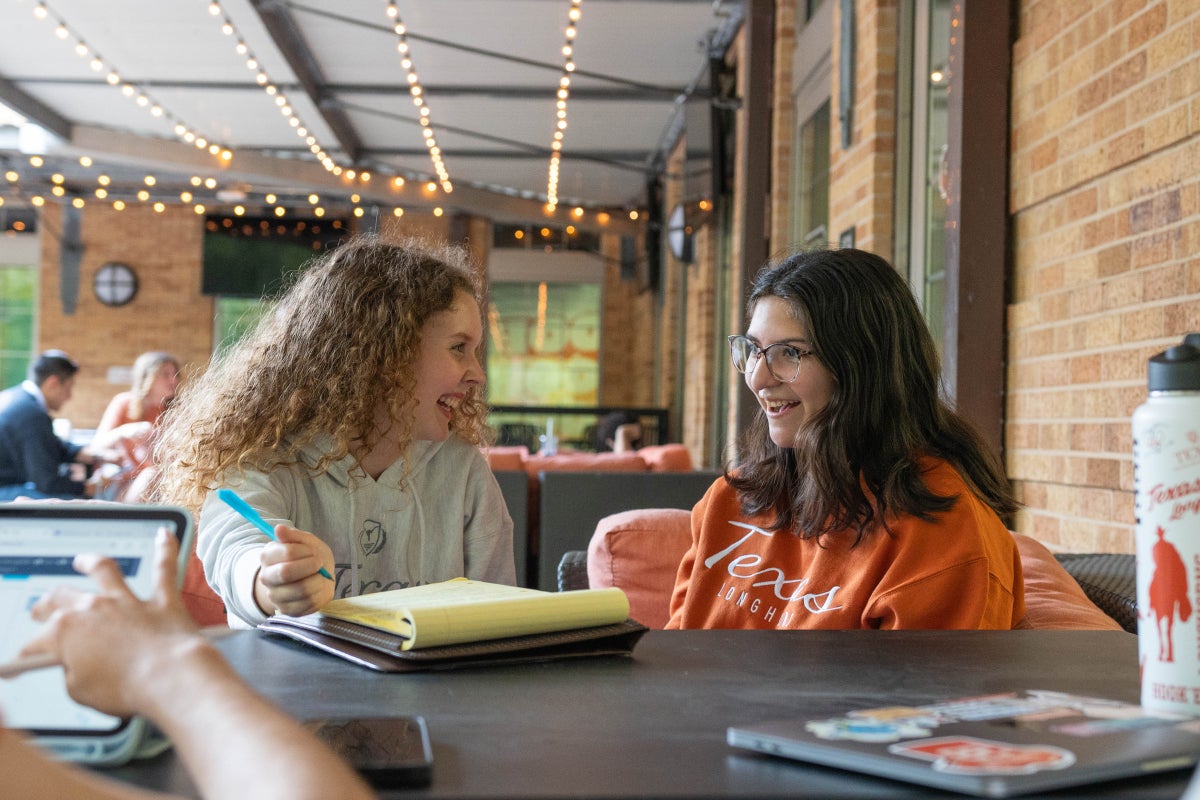 3. Two UT students study together at Cypress Bend Cafe's outdoor patio.