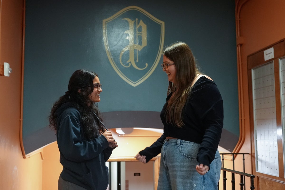 Two UT students converse in a hallway in Prather Hall
