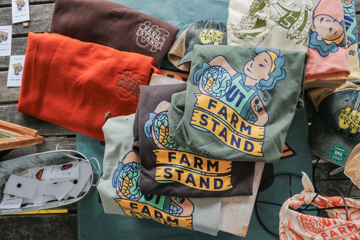 A close up of shirts and other merch featuring the UT Farm Stand logo