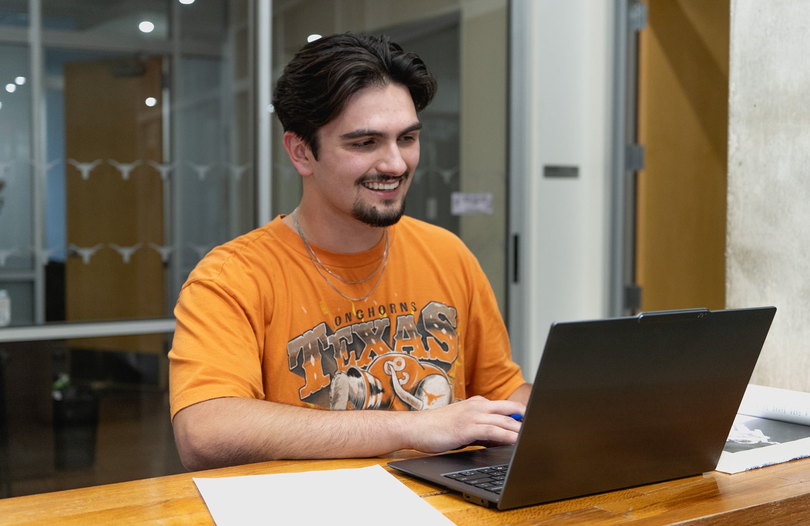 A student is smiling and looking at a laptop