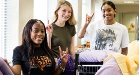 Image of three studnets posing for the camera with the Bevo hand sign