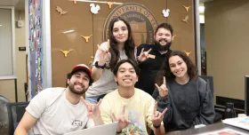 Five UT students pose together making the Hook ‘em hand sign at the Jester West Hall front desk