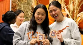  Two UT students hold up crafts at a Friendsgiving event in the dining hall.