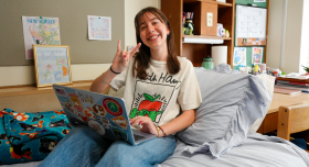 UT student posing with Hook ‘em hand sign inside their room at Kinsolving residence hall.