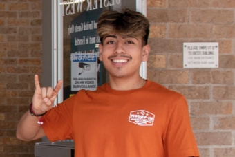 Two UHD student employees smiling and posing with the Hook ‘em hand sign