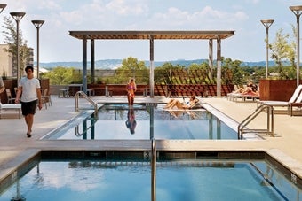 Students walking and lounging at the 2400 Nueces Apartment rooftop pool