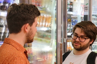 Two students talking to each other at Kin’s Market, the convenience store inside Kinsolving Residence Hall.