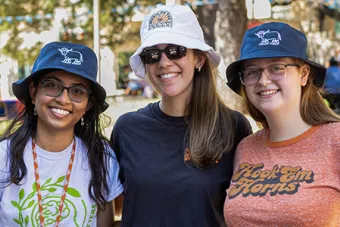 Three UT students pose together with UHD bucket hats at the fall 2023 Northside Bash