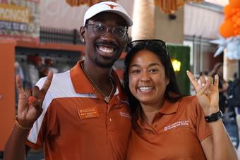Two UHD employees with Hook'em horns gestures