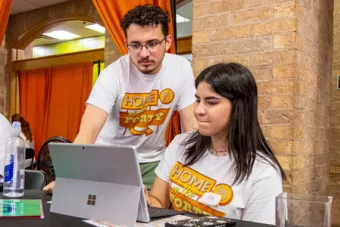 : Two UT students check guests in on a tablet at New Student Orientation.