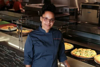 A UT staff member stands in front of a pizza buffet in J2 Dining