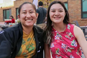Two students posing in front of the east campus graduate apartments