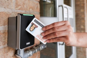 A person tapping their UT ID card on a door card reader.