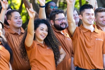 A group of UT residence life staff members pose together while making the Hook ‘em hand sign