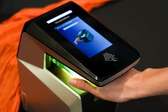 A UT student waves their hand through a hand scanner
