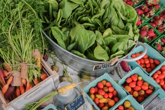 A close up of produce featuring carrots, bok choy, cherry tomatoes and strawberries
