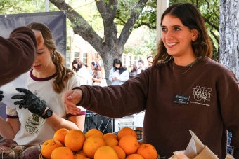A UT student smiles while handing over produce at a UT Farm Stand market
