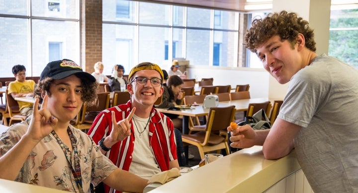 Three students posing for a picture with their meals inside J2 Dining