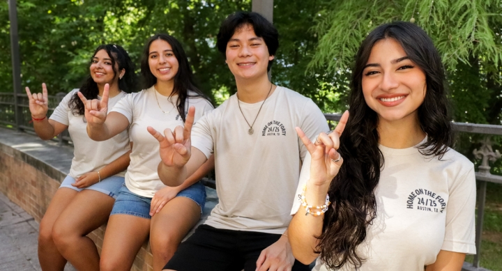 Four UT students pose together in Home on the Forty shirts outside San Jacinto Hall