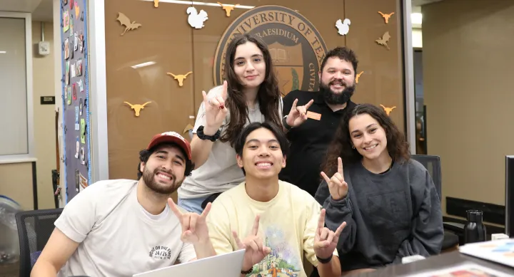 Five UT students pose together making the Hook ‘em hand sign at the Jester West Hall front desk