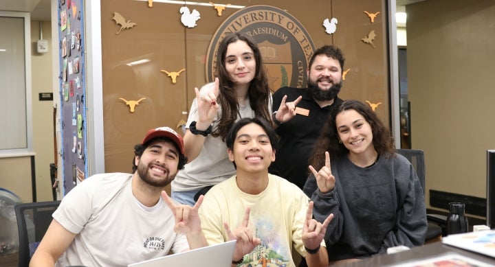 Five UT students pose together making the Hook ‘em hand sign at the Jester West Hall front desk