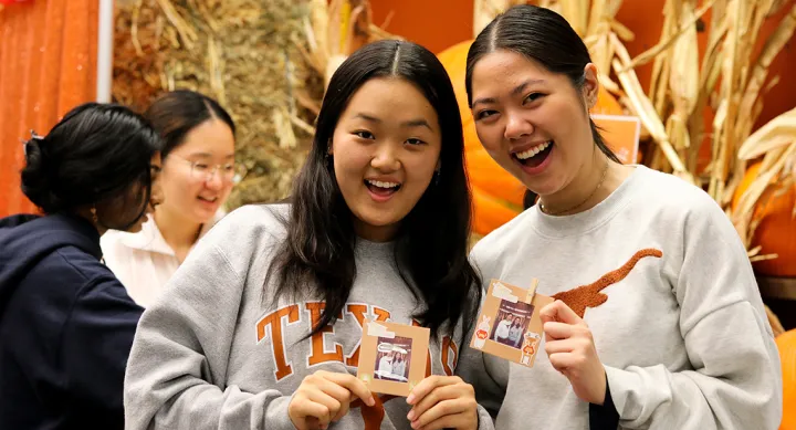 Enjoying Cooler Weather on the Forty Acres Two UT students hold up crafts at a Friendsgiving event in the dining hall.
