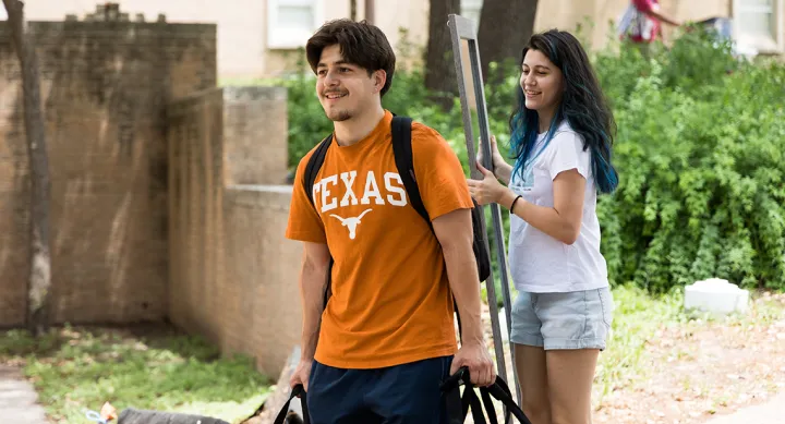 Two UT students carrying a mirror and other items at spring checkout
