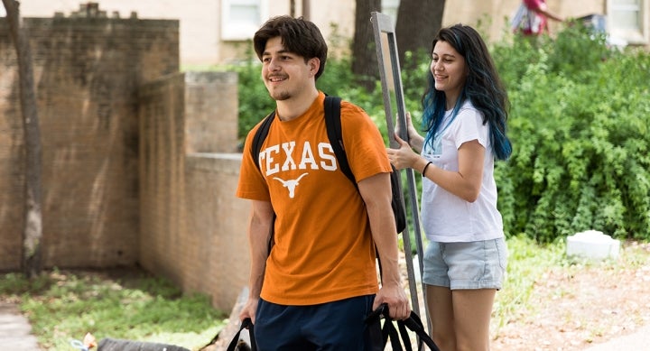 Two UT students carrying a mirror and other items at spring checkout