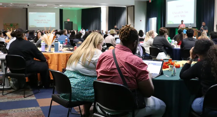 Event guests sit around tables while listening to presenters in San Jacinto Multipurpose Room.